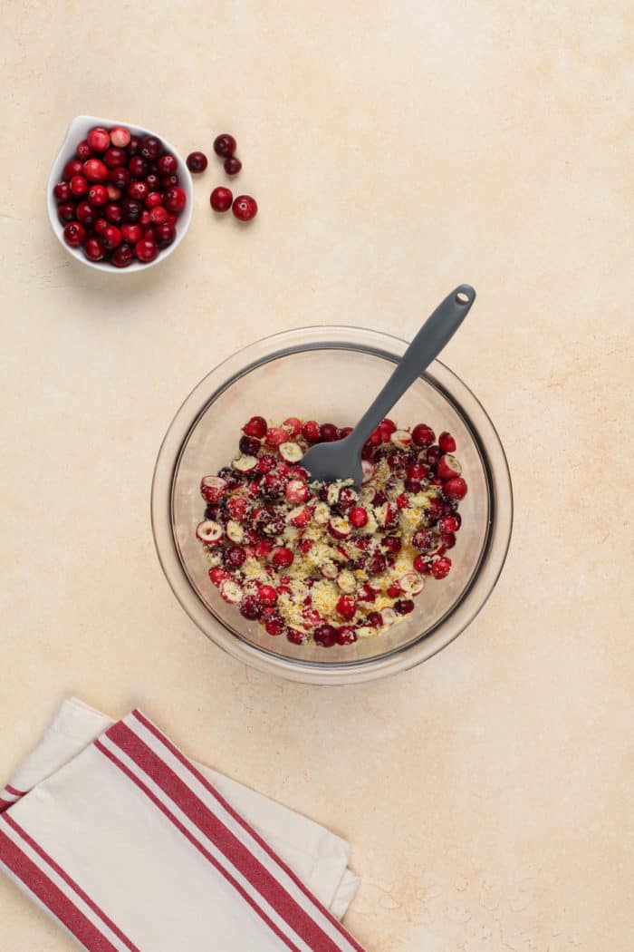 Chopped fresh cranberries tossed with sugar in a glass mixing bowl.