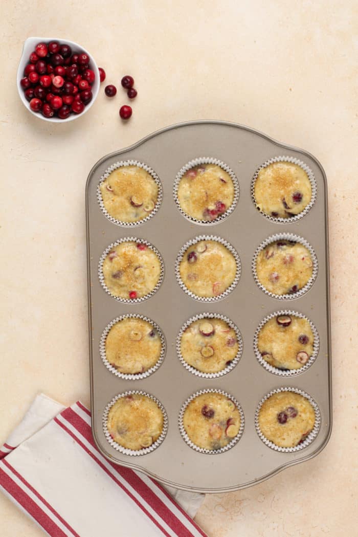 Unbaked cranberry orange muffins in a muffin tin, ready to go in the oven.