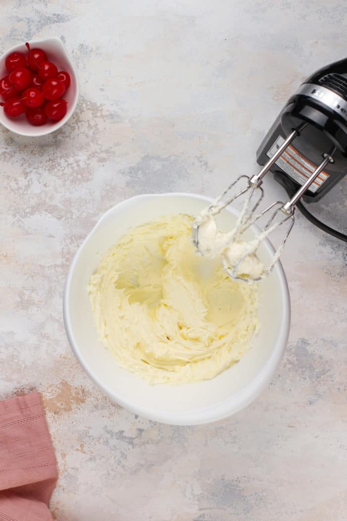 Whipped butter in a white mixing bowl next to an electric mixer.