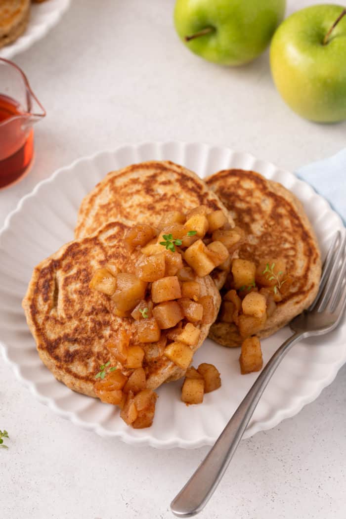 Apple compote on top of oatmeal pancakes on a white plate.