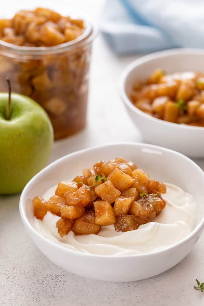 Apple compote on top of yogurt in a white bowl.