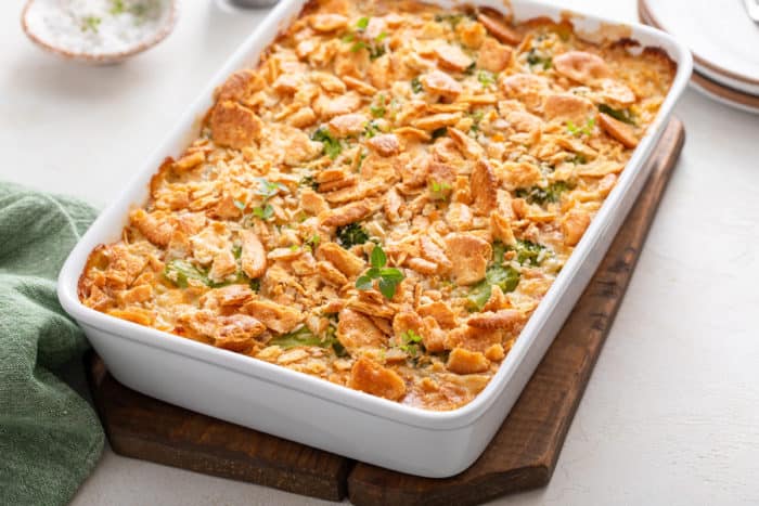 White casserole dish filled with chicken broccoli rice casserole set on a wooden trivet.