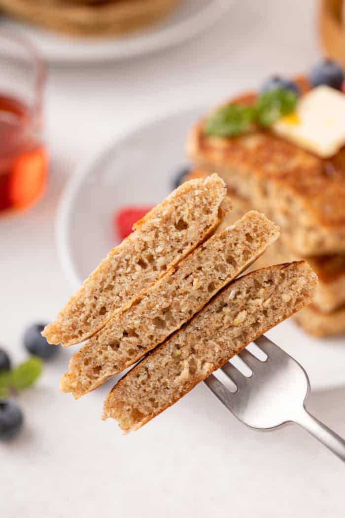 Fork holding up a bite of oatmeal pancakes to show the inside, fluffy texture.