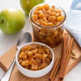 Two containers filled with apple compote on a wooden board.
