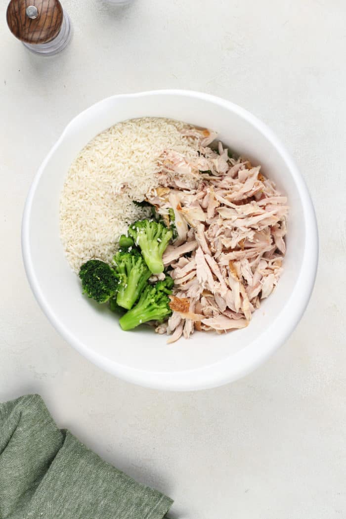 Ingredients for chicken broccoli rice casserole in a large, white mixing bowl.