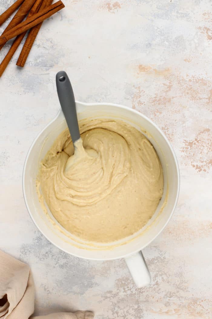 Batter for cinnamon roll cake in a white mixing bowl.