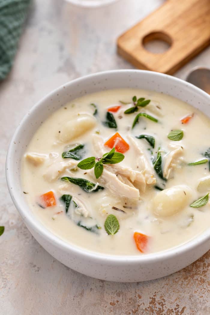 Close up of white bowl filled with chicken and gnocchi soup.