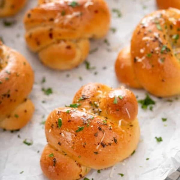 Close up of garlic knots arranged on a piece of parchment paper on top of a wire rack.