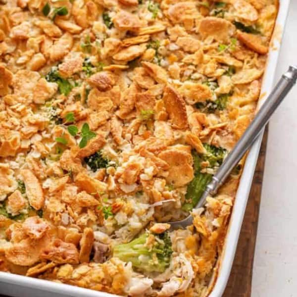 Casserole dish of chicken broccoli rice casserole with a serving spoon in the corner of the casserole.
