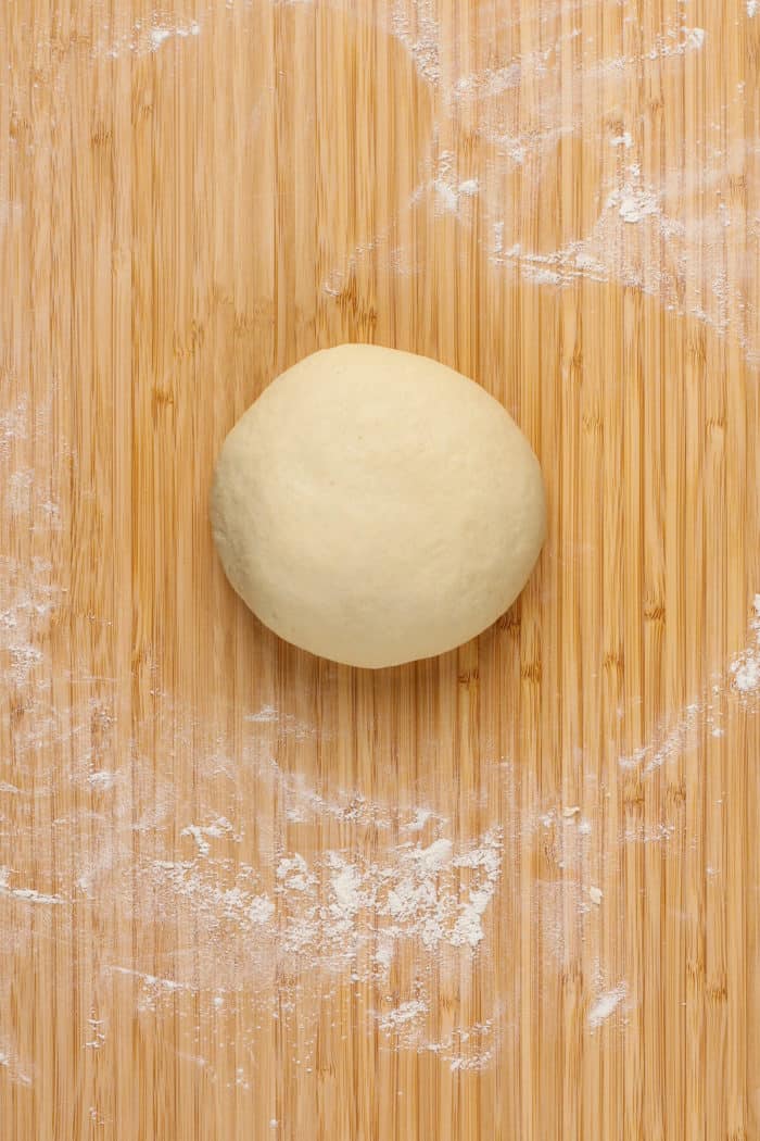 Kneaded dough for garlic knots on a wooden board.