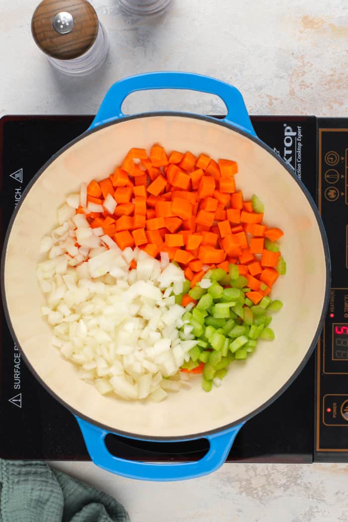 Mirepoix added to a blue dutch oven.