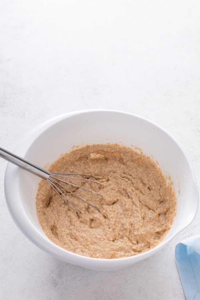 Oatmeal pancake batter in a white mixing bowl.