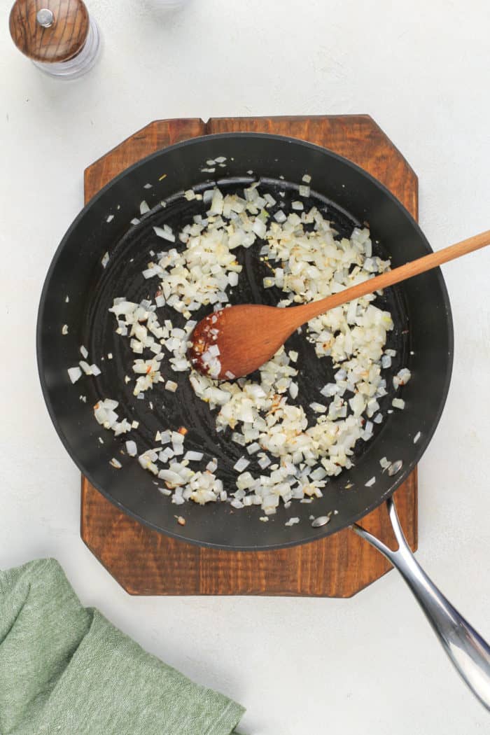 Black skillet with sauteed onions and garlic in the pan.