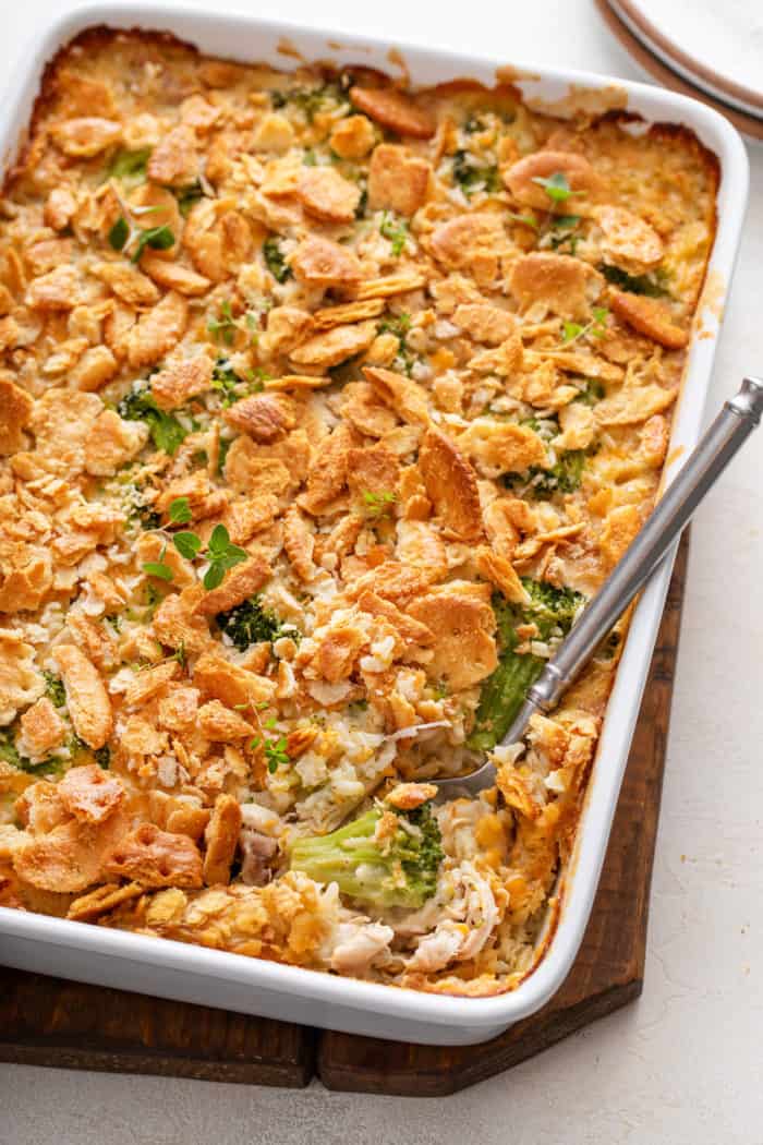 Casserole dish of chicken broccoli rice casserole with a serving spoon in the corner of the casserole.