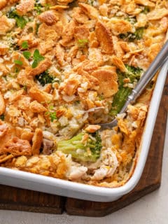 Serving spoon in the corner of a baking dish full of chicken broccoli rice casserole.