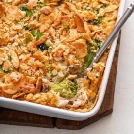 Serving spoon in the corner of a baking dish full of chicken broccoli rice casserole.