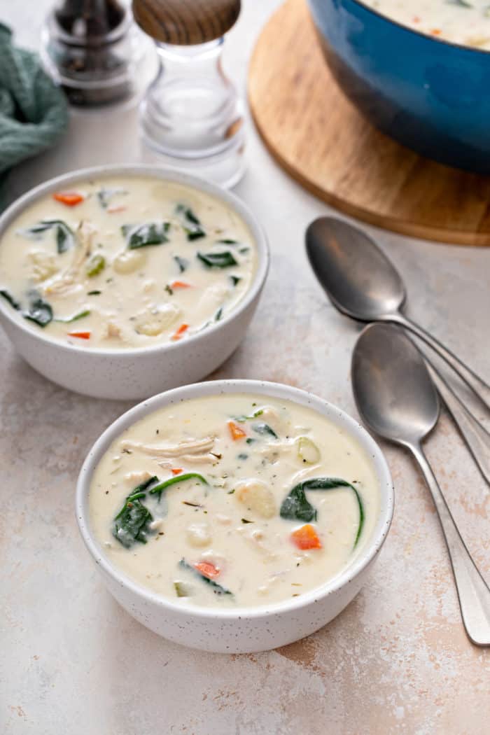 Two white bowls filled with chicken and gnocchi soup.