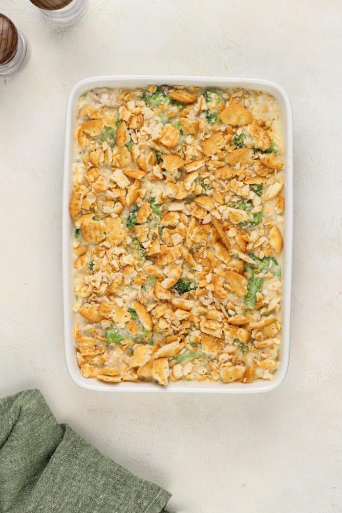 Unbaked chicken broccoli rice casserole, topped with crackers, in a white baking dish.