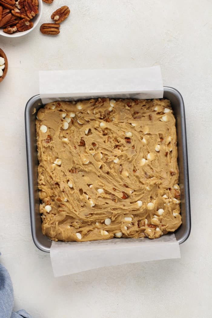 Unbaked white chocolate pecan blondies in a baking pan, ready to go in the oven.