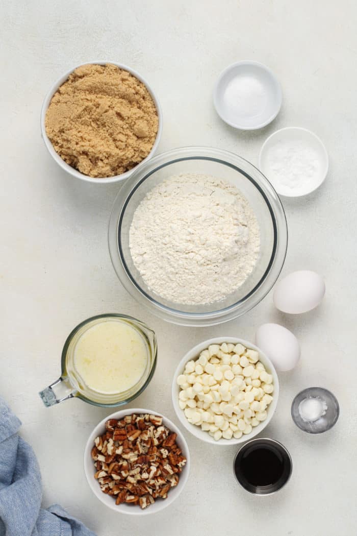 Ingredients for white chocolate pecan blondies arranged on a white countertop.