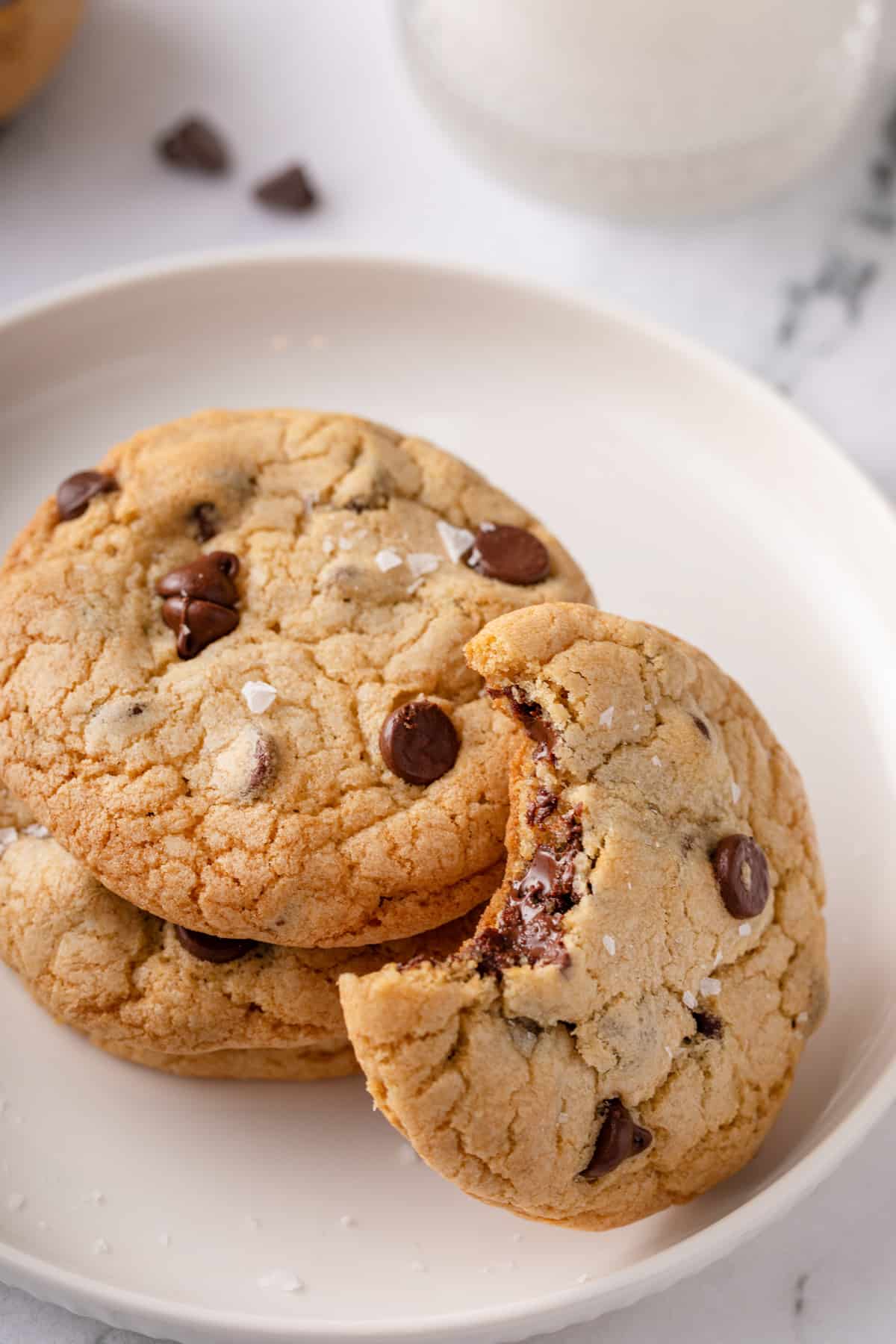 Three grand floridian chocolate chip cookies on a white plate. Two are stacked and the third has a bite taken from it and is leaning against the other two.