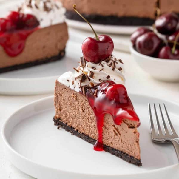 Slice of black forest cheesecake on a white plate.