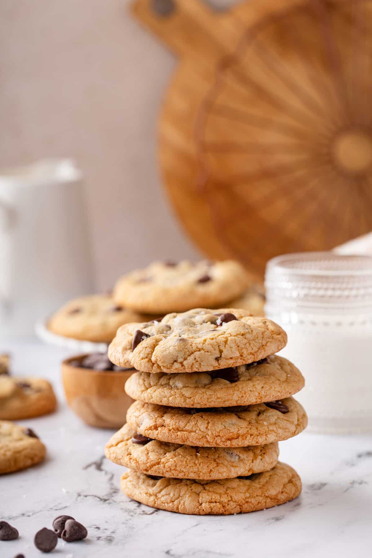 Five grand floridian chocolate chip cookies stacked in front of a glass of milk.