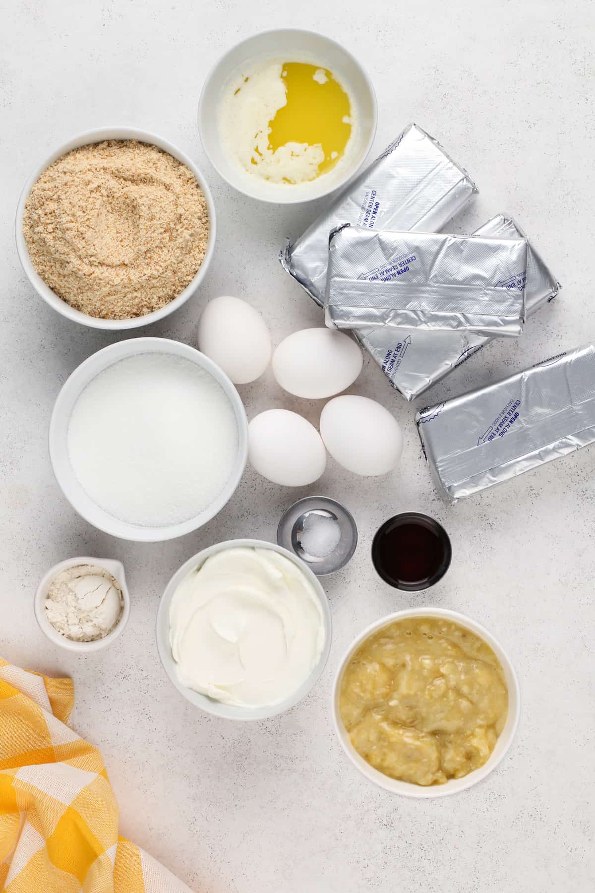 Ingredients for banana pudding cheesecake arranged on a light countertop.