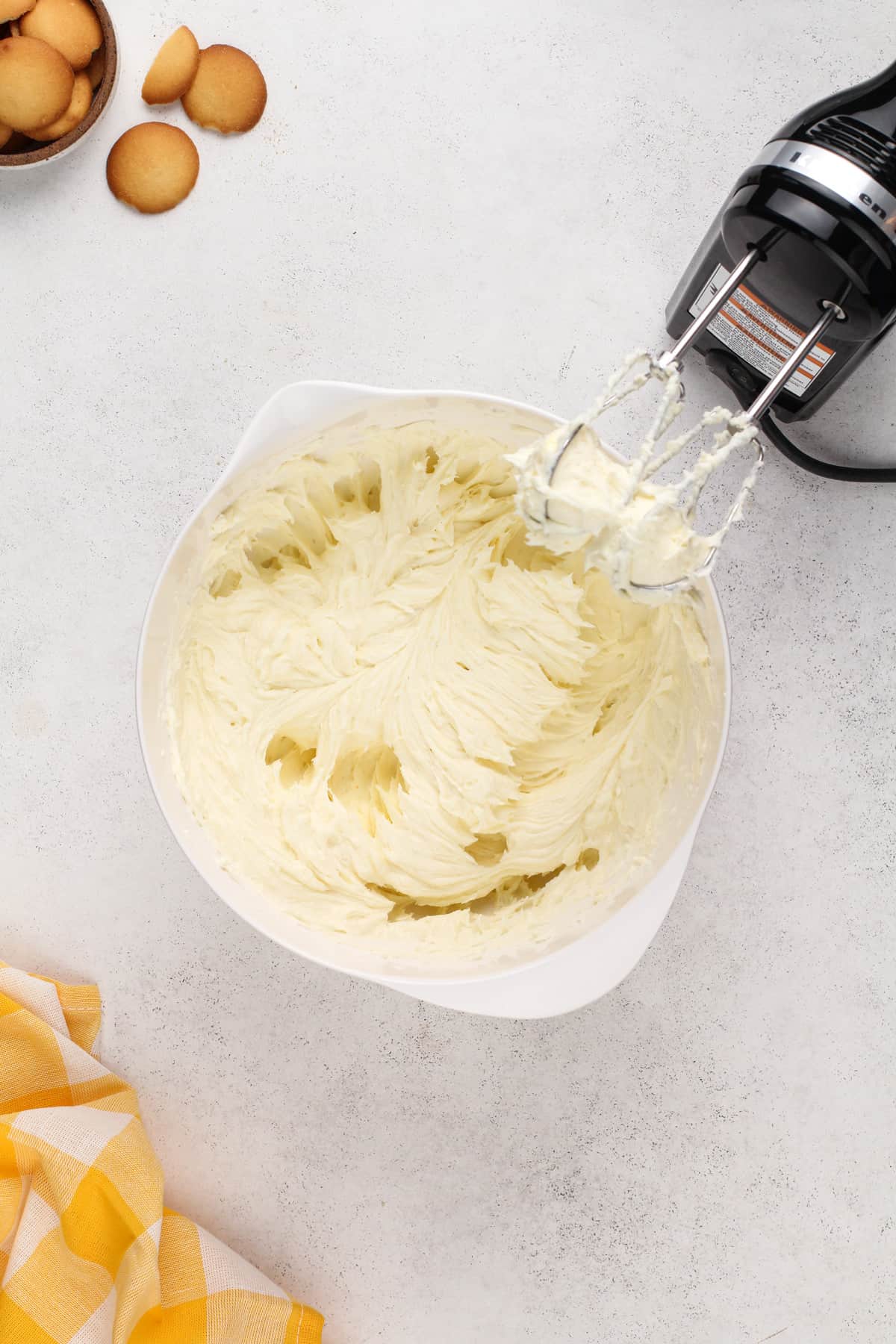 Cream cheese beaten with sugar and flour in a white bowl.