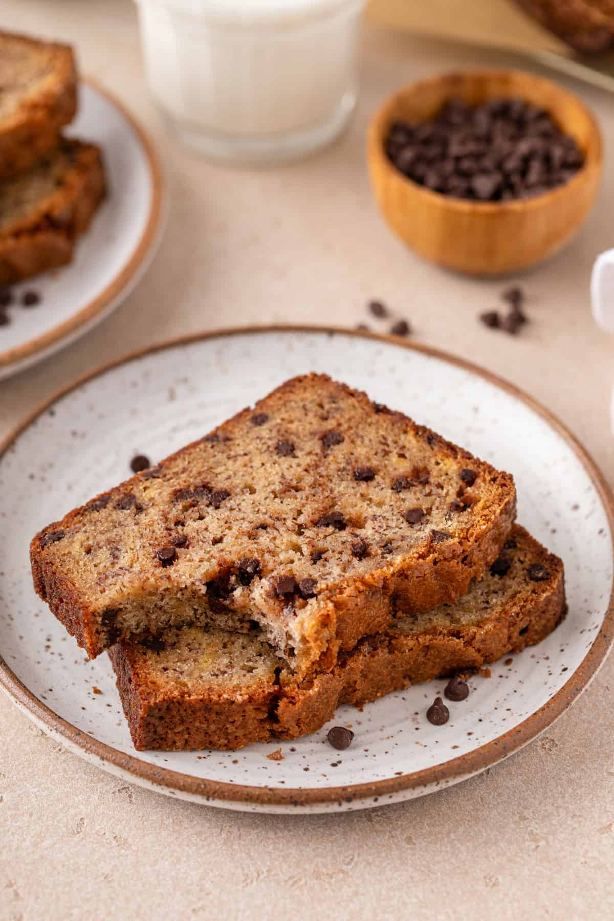 Two slices of chocolate chip banana bread on a plate, with a bite taken from the top slice.