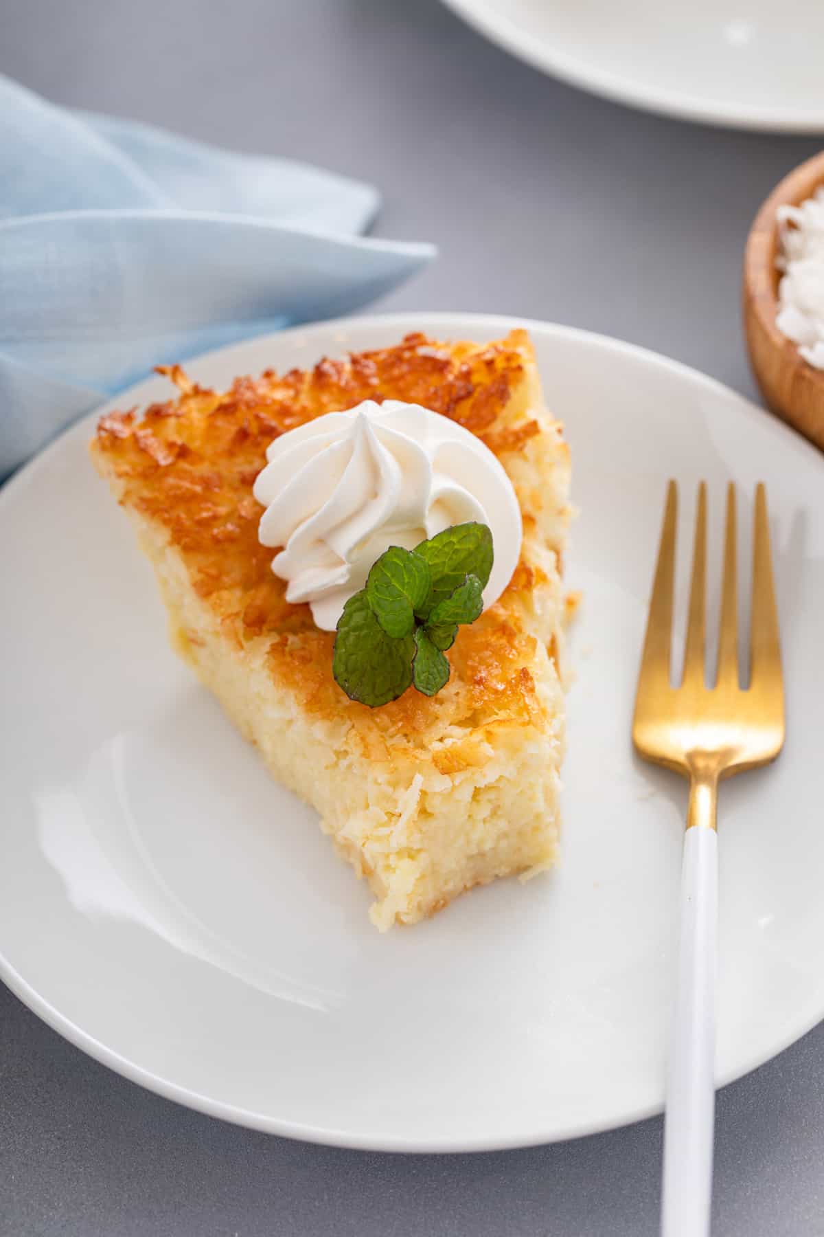 Bite taken from a slice of impossible coconut pie on a white plate.