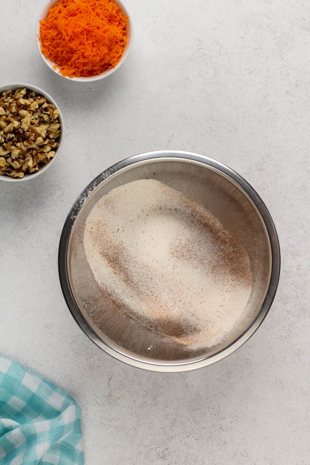 Dry ingredients for carrot bundt cake sifted together in a metal bowl.