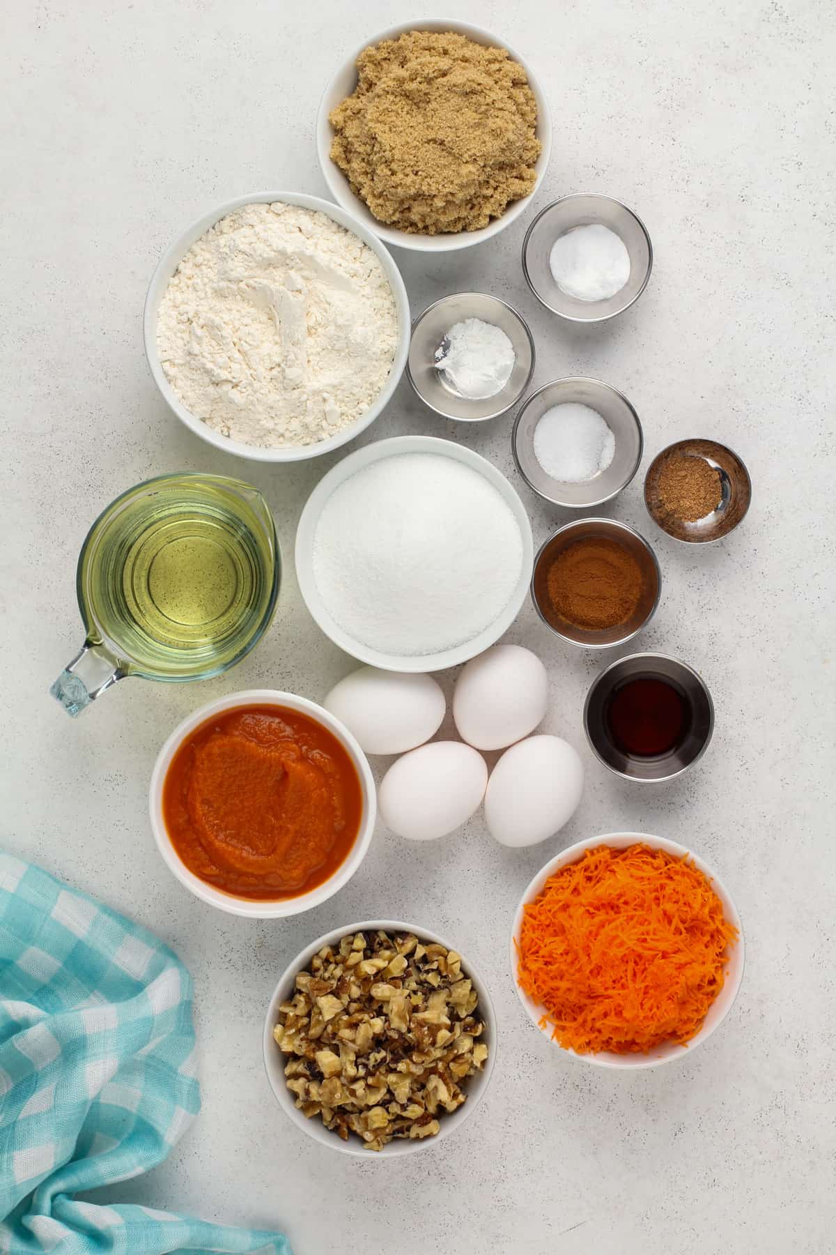 Ingredients for carrot bundt cake arranged on a light-colored countertop.