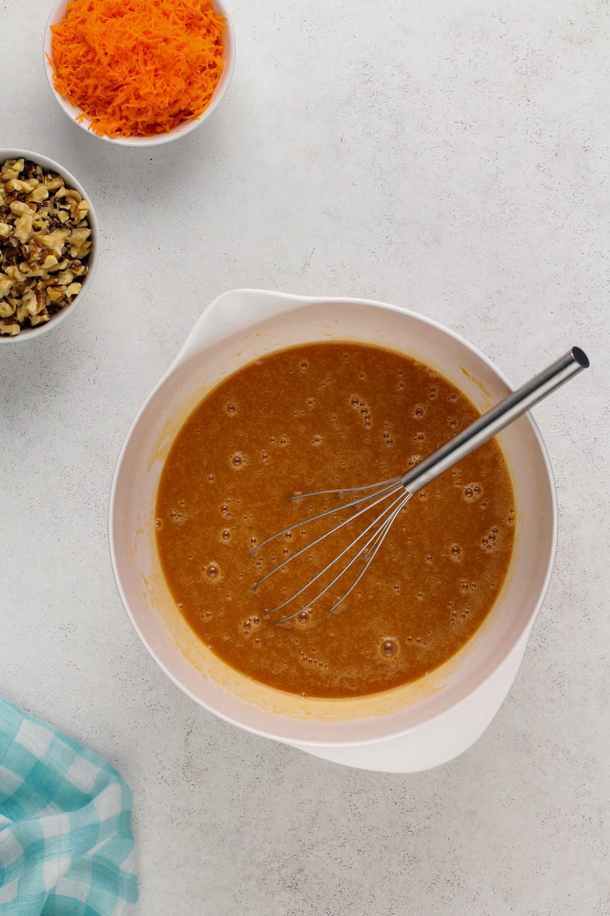 Wet ingredients for carrot bundt cake whisked together in a white bowl.