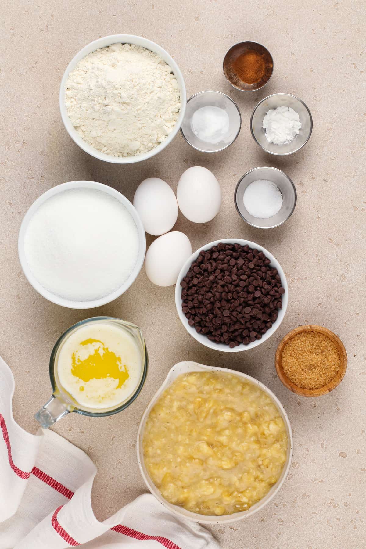 Chocolate chip banana bread ingredients arranged on a beige countertop.