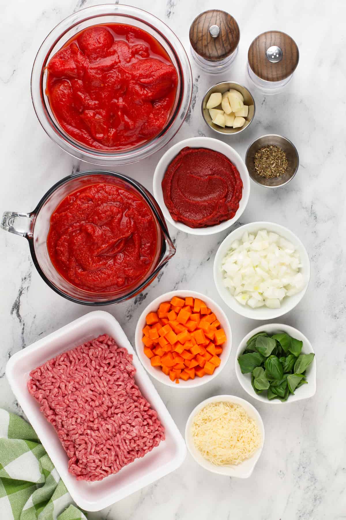 Ingredients for crockpot spaghetti sauce arranged on a marble countertop.