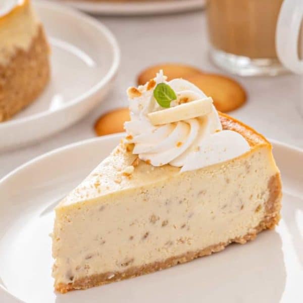 Side view of a slice of banana pudding cheesecake on a white plate.