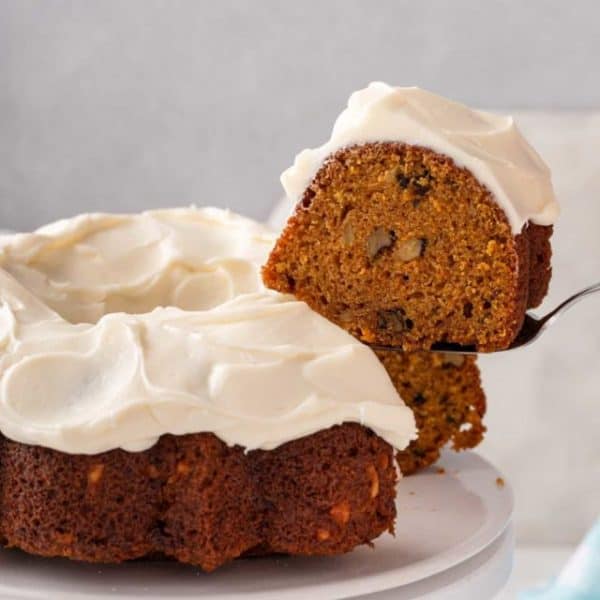 Cake server lifting up a slice of carrot bunt cake from a cake plate.