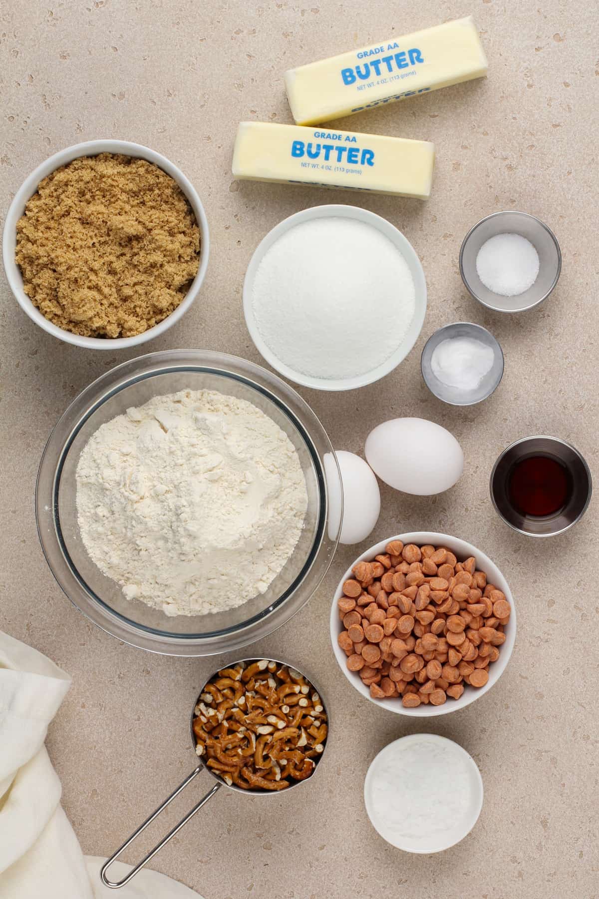 Ingredients for salted caramel pretzel cookies arranged on a beige countertop.