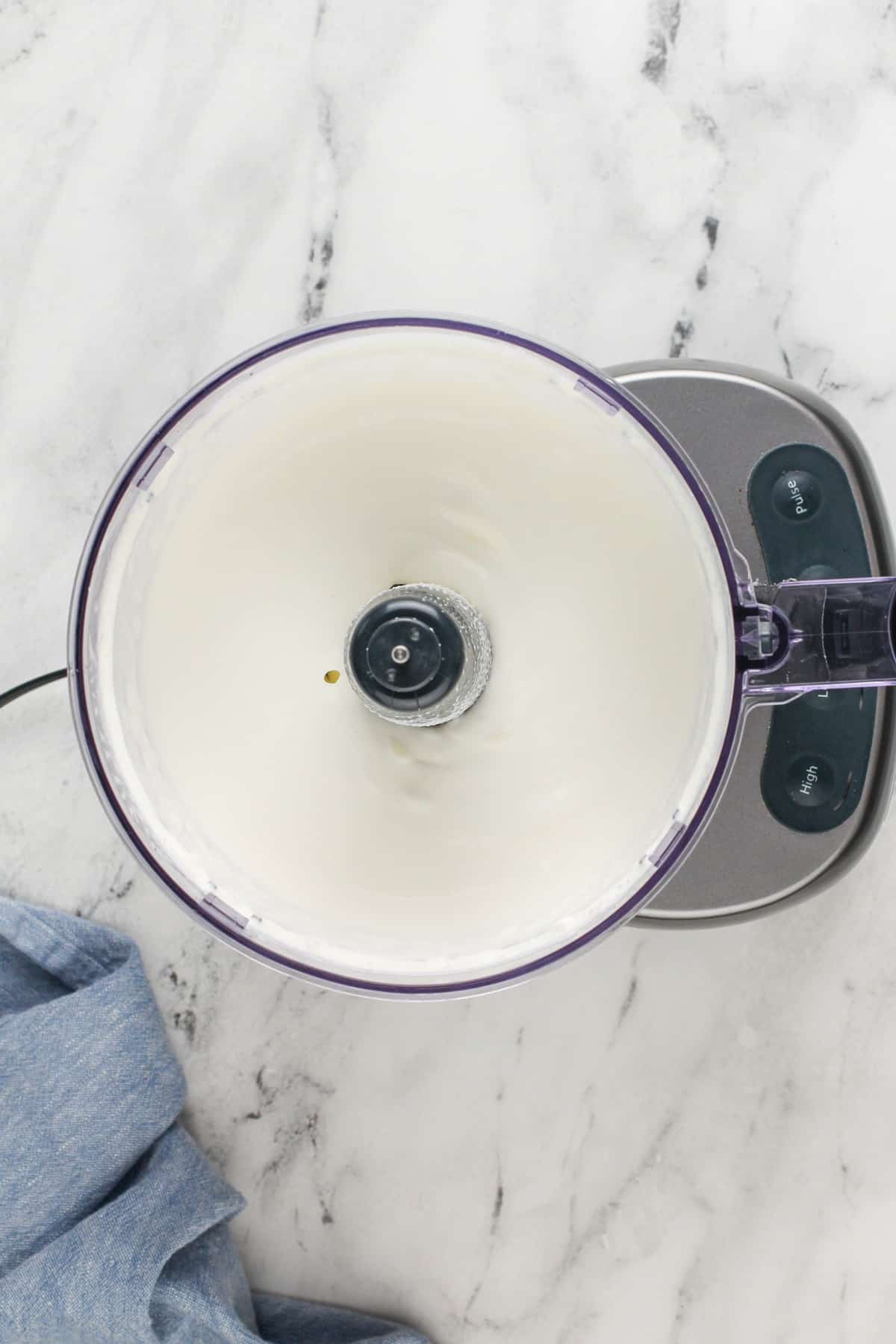 Butter being mixed in the bowl of a food processor.