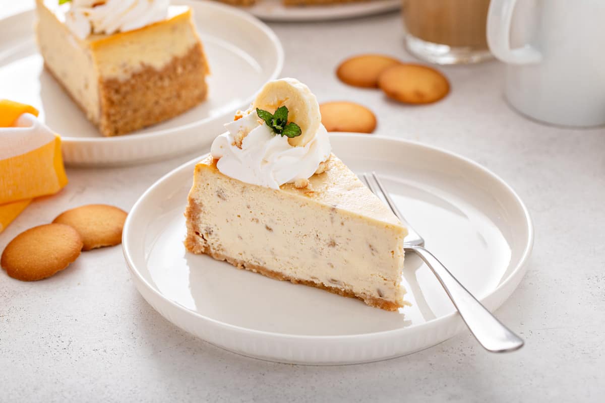 Slice of banana pudding cheesecake topped with whipped cream and a slice of banana.