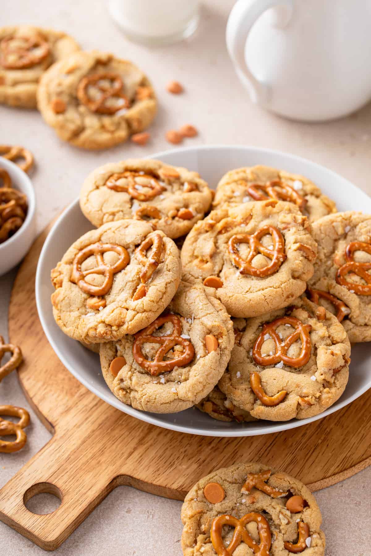 Several salted caramel pretzel cookies on a large plate set on a wooden board.