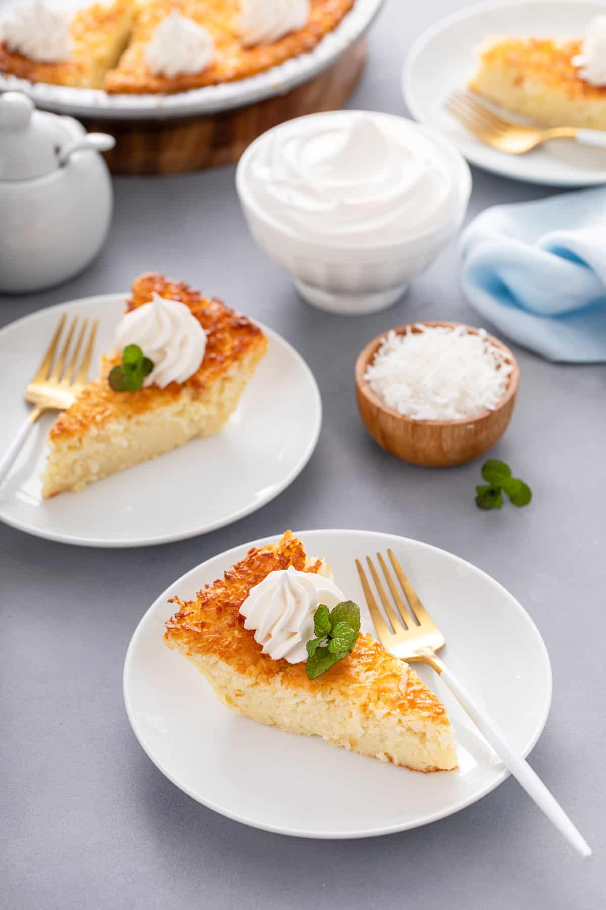 Two white plates, each holding a slice of impossible coconut pie and a fork.