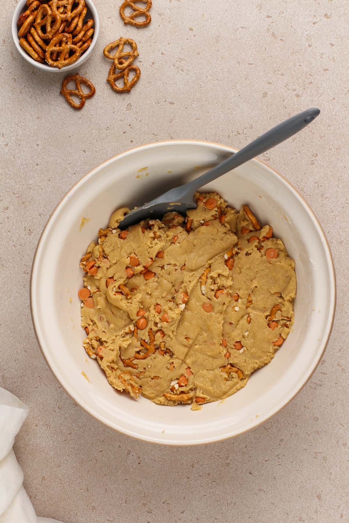 Cookie dough for salted caramel pretzel cookies in a white mixing bowl.