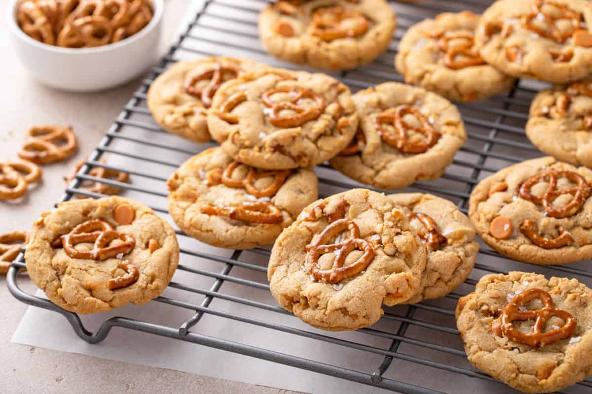 Salted caramel pretzel cookies scattered on a wire cooling rack.