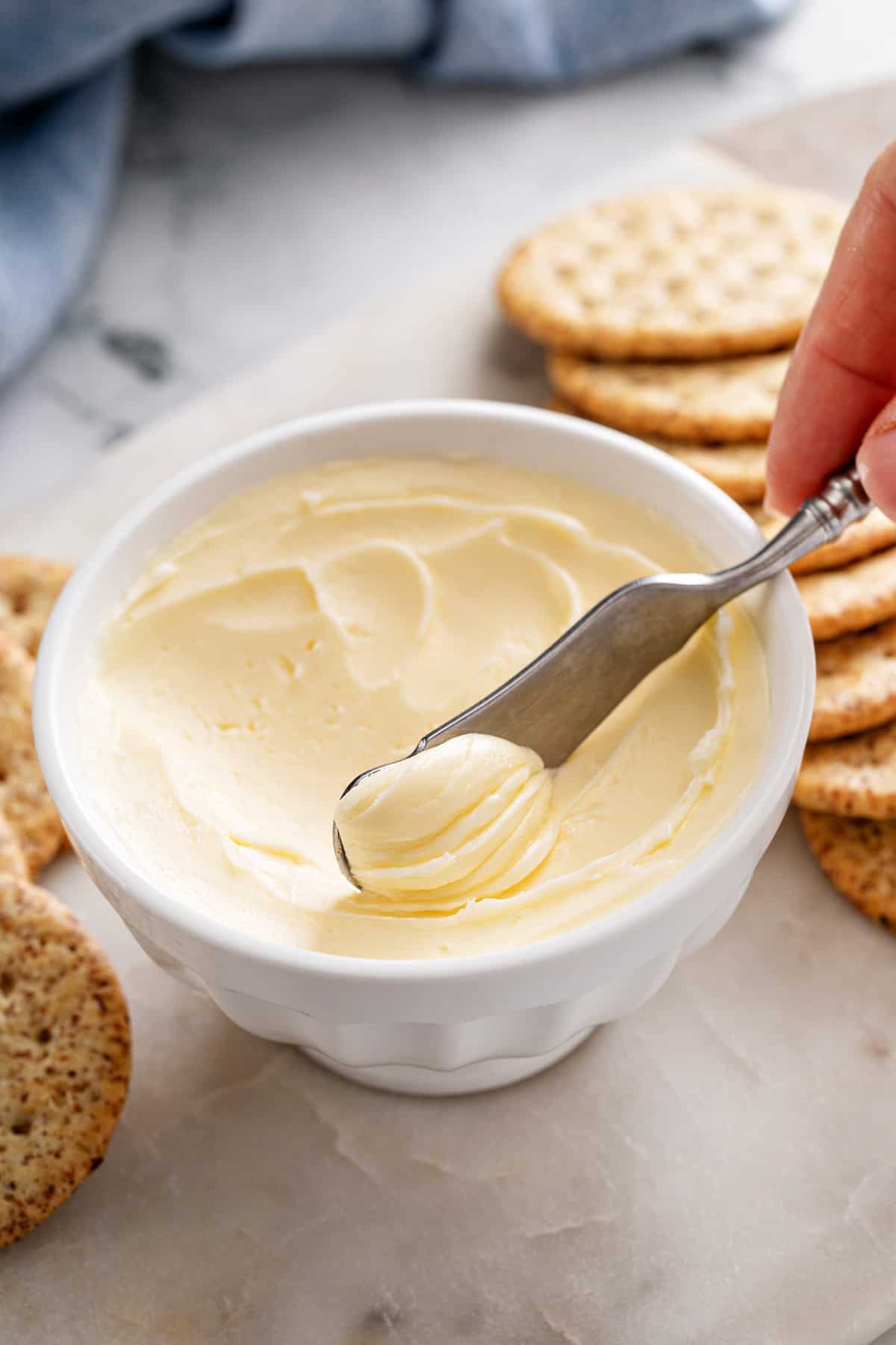 Butter knife scooping homemade butter out of a white bowl.