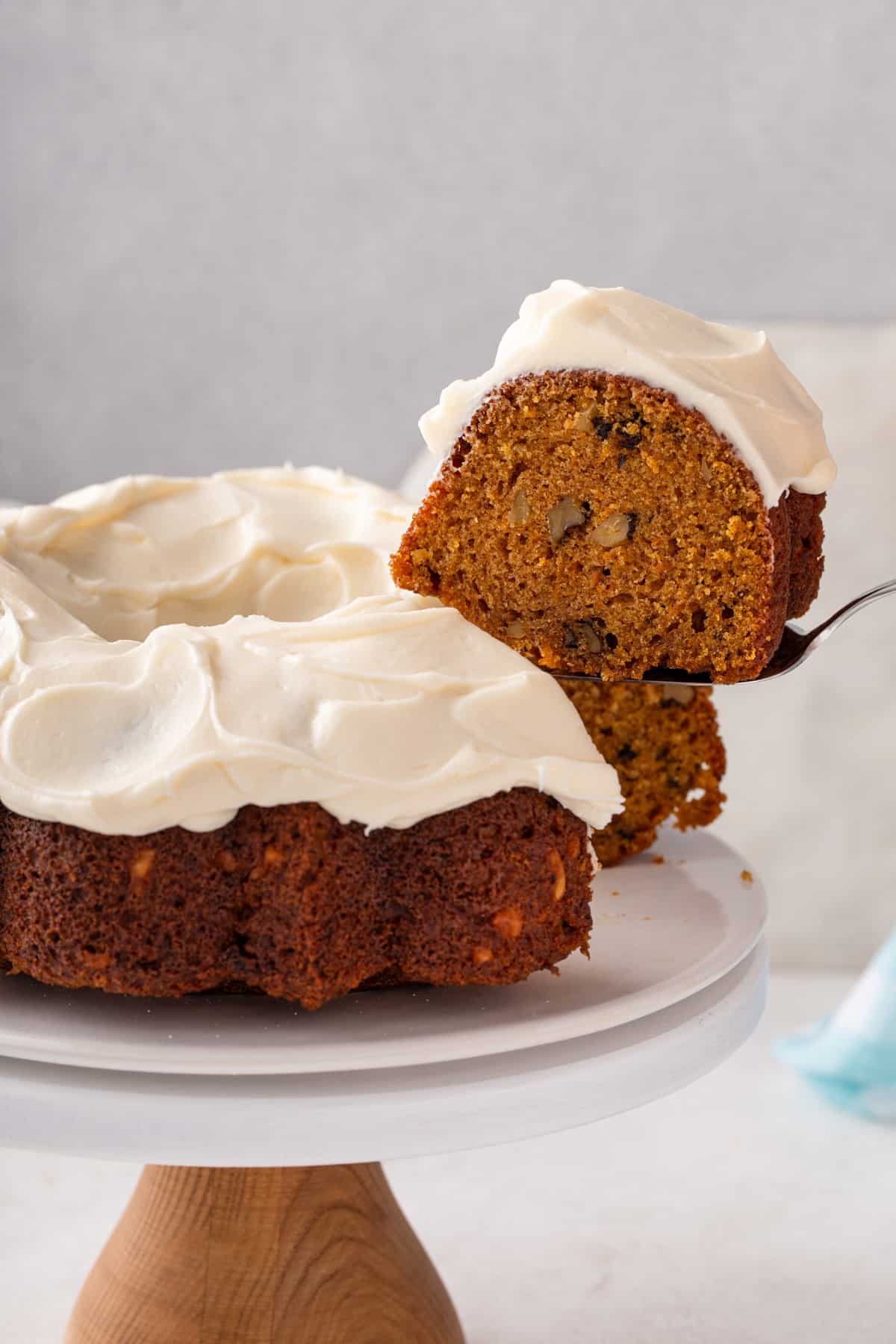 Cake server lifting up a slice of carrot bunt cake from a cake plate.