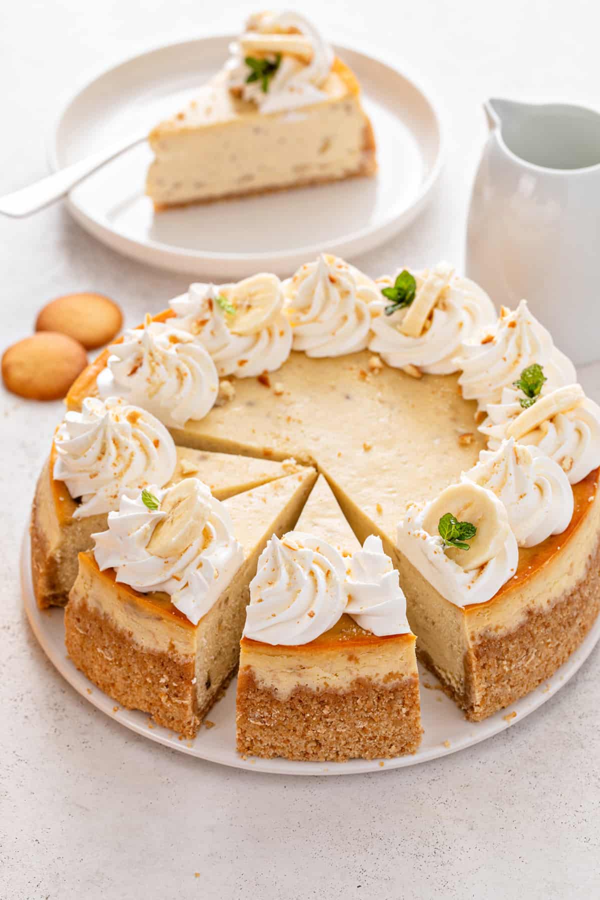 Sliced banana pudding cheesecake topped with whipped cream and fresh banana slices.