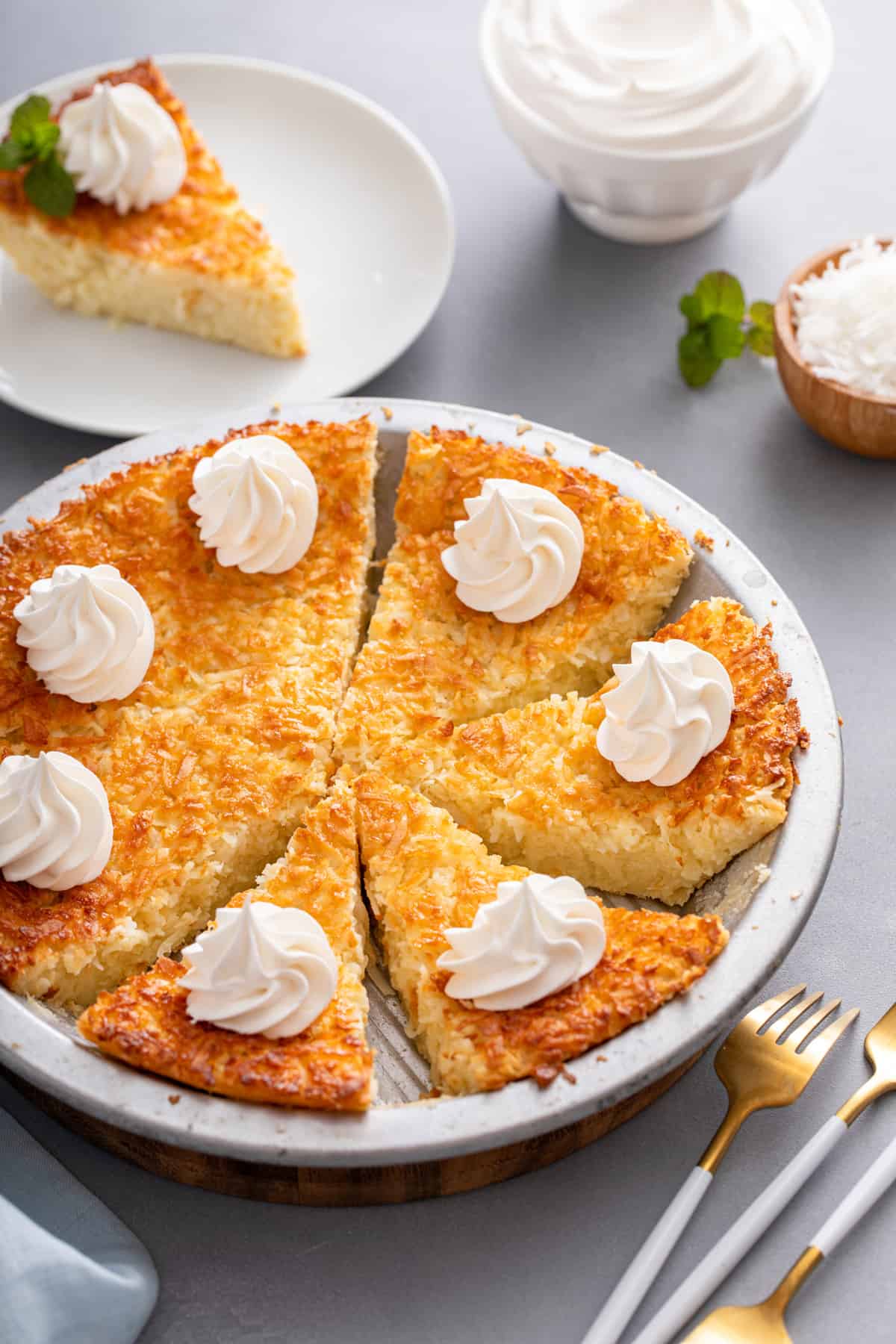 Sliced impossible coconut pie garnished with whipped cream in a pie plate.