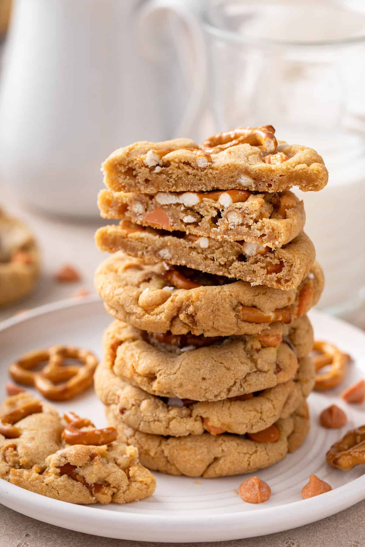 Several stacked salted caramel pretzel cookies. The top cookies are cut in half to show the chewy inner texture.